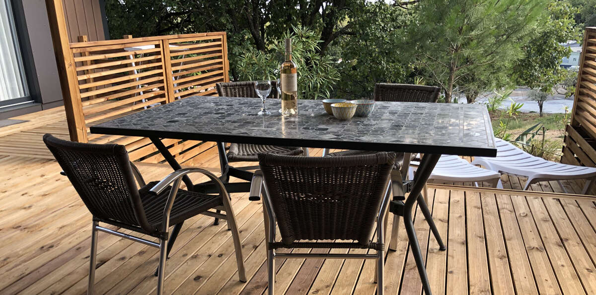 table d'un mobil home avec une bouteille de vin dans le Camping Paradis Domaine de Miremer