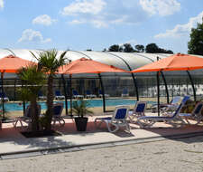 piscine intérieure et transats en extérieur dans le Camping Paradis Les Etangs de Plessac