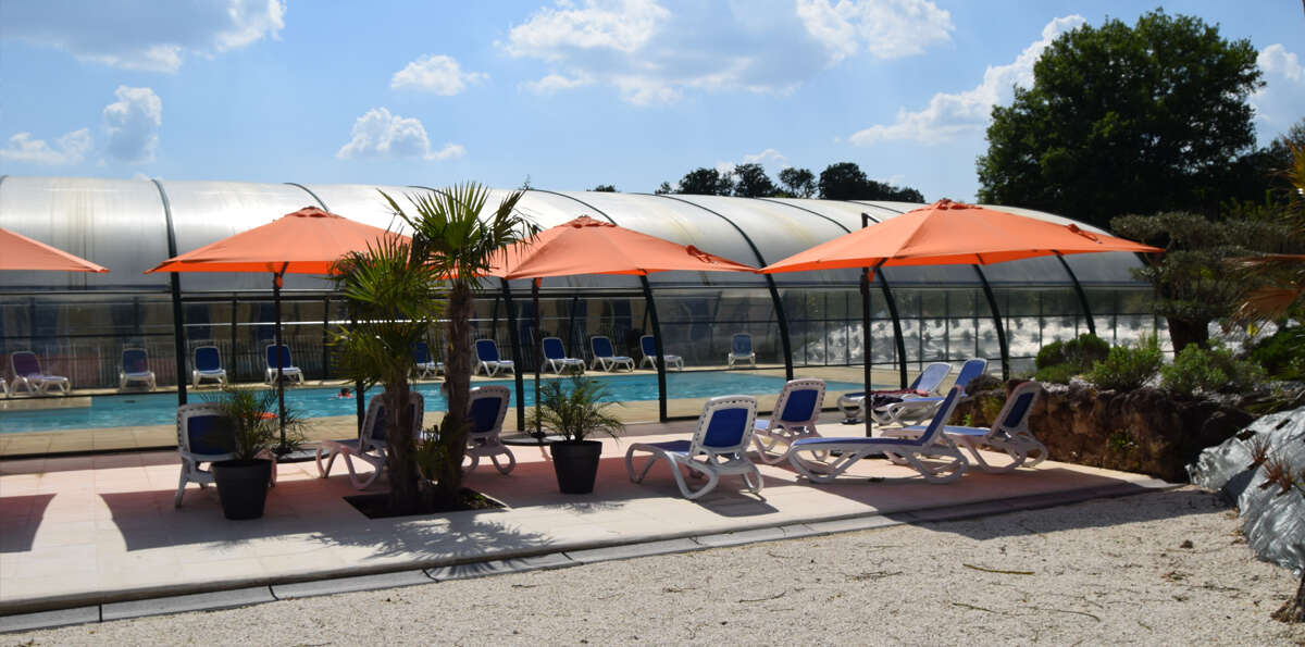 piscine intérieure et transats en extérieur dans le Camping Paradis Les Etangs de Plessac