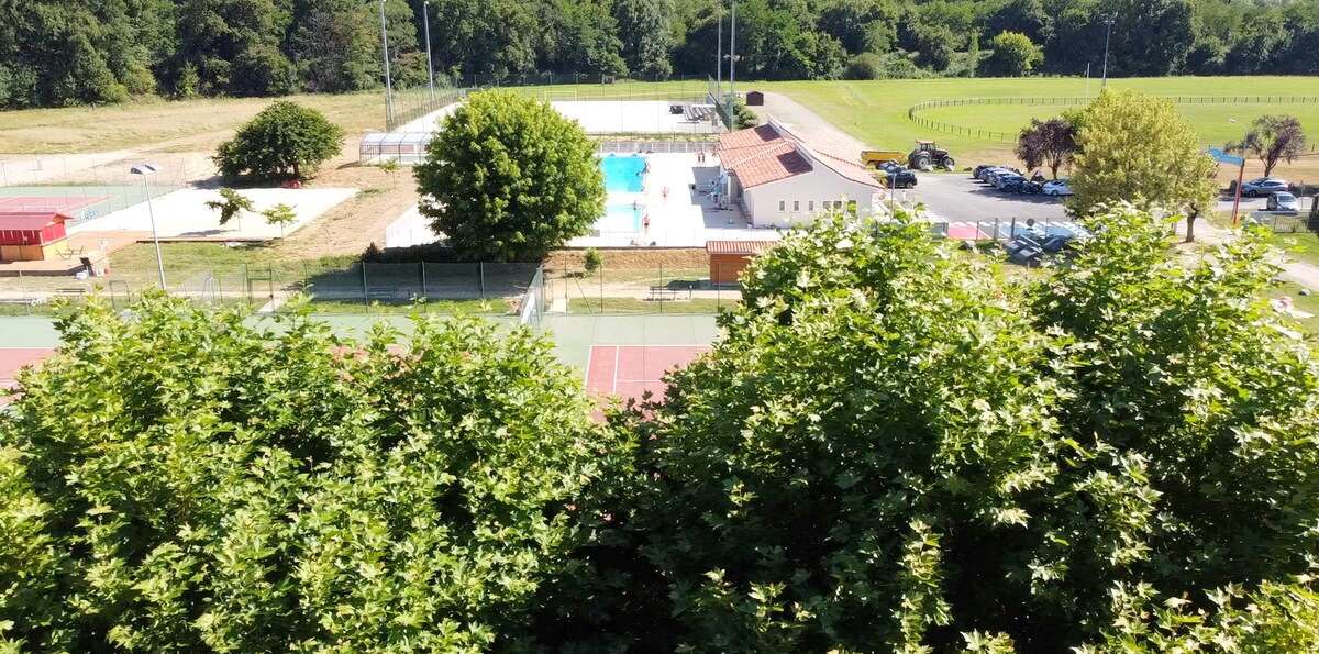 terrains de tennis et piscine derrière les arbres